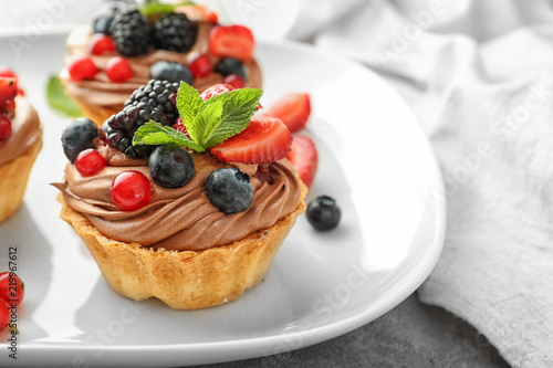 Tasty tartlets with chocolate cream and berries on plate  closeup