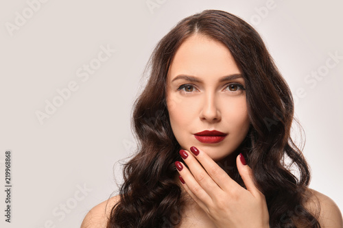 Beautiful young woman with professional manicure on light background