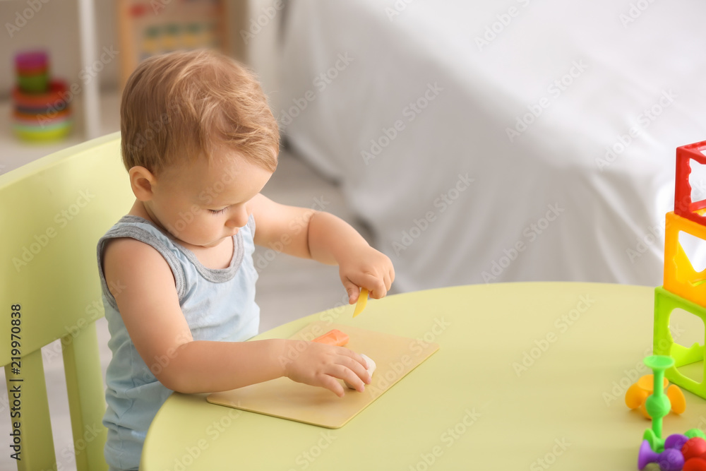 Cute little boy using play dough at table indoors Cute little boy using play dough at table indoors