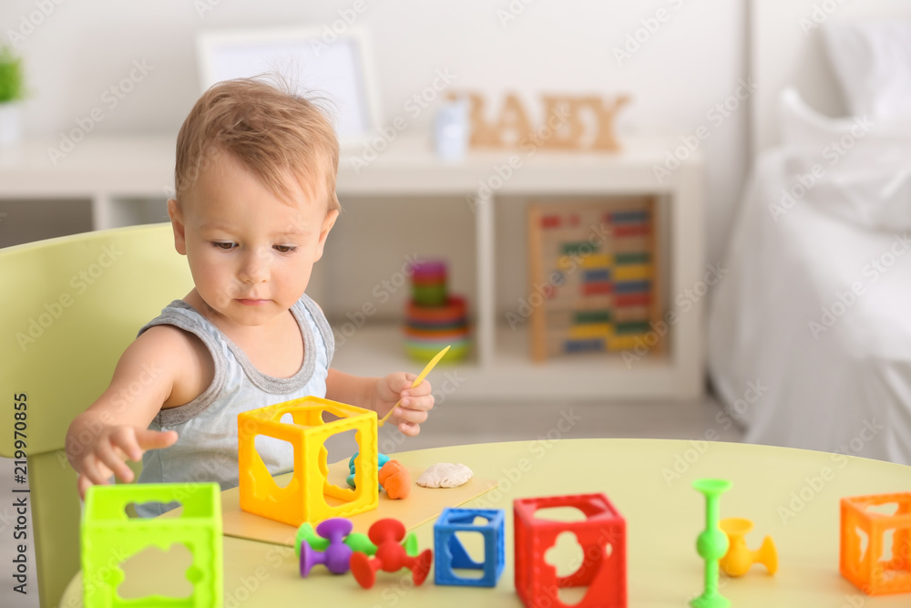 Fototapeta premium Cute little boy playing with toys at table indoors