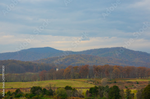 View of distant mountains (Blue ridge mountains) and Forest with Field. Beautiful Sky and clouds on background. Fall autumn season Foliage.