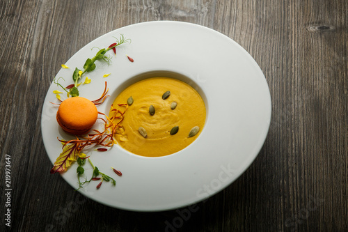 top view of fresh pumpkin cream soup with orange macaroon decoration
