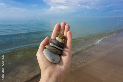 Different color stones in the hand on the background of Baltic sea in summer