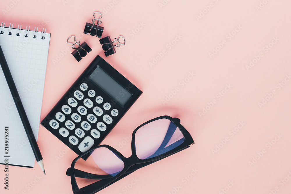 Notepad, calculator, pencil and glasses on pink background. Top view, flat lay Notepad, calculator, pencil and glasses on pink background. Top view, flat lay