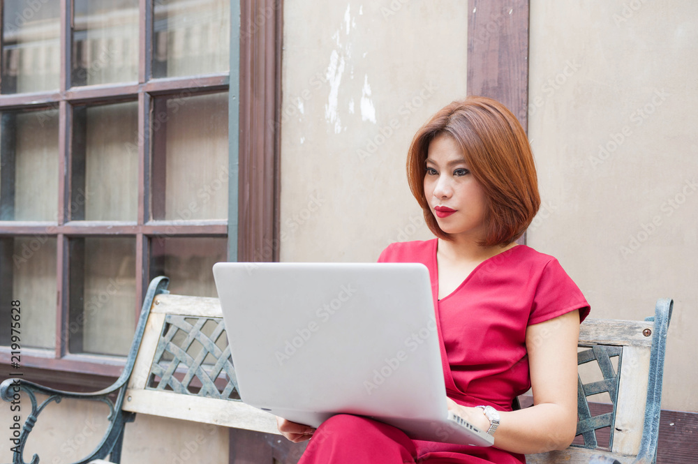 Fototapeta premium Red dress Asian women smile and enjoy with work in her laptop ,Red lips women