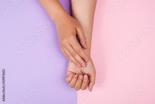 Hand and nail care concept. Female manicure. Woman s hands on pink and violet background. Beautiful healthy nails. Pastel pink women manicure.