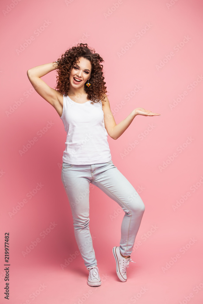 Full length portrait of a smiling woman holding copyspace on the palm isolated on a pink background. Looking at camera. Full length portrait of a smiling woman holding copyspace on the palm isolated on a pink background. Looking at camera.