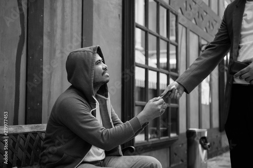 Фотография A man give money for homeless man,Homeless man happy with assistance from humani