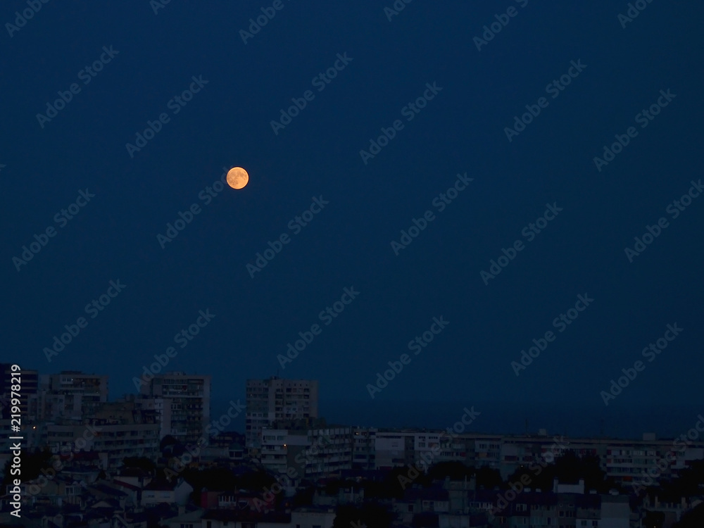 Full moon of reddish hue rose above the sleeping seaside town Full moon of reddish hue rose above the sleeping seaside town