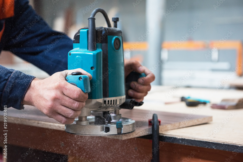 Furniture production or craft concept: worker polishing the wood surface of furniture part with polish machine Furniture production or craft concept: worker polishing the wood surface of furniture part with polish machine