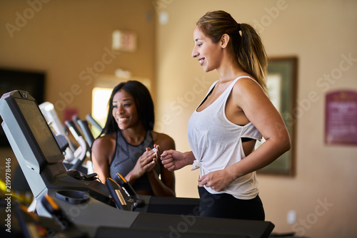 personal trainer teaching woman how to use treadmill in gym