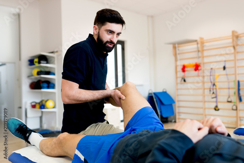 Male therapist treating knee of sporty patient
