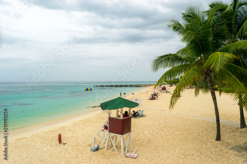 Life Guard, coconut trees and beach goers on a cloudy day at the beach in Jamaica