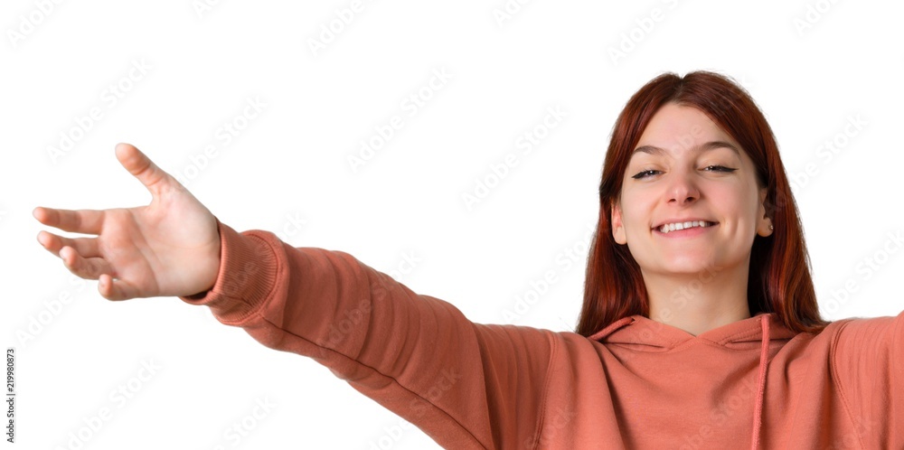 Young redhead girl with pink sweatshirt presenting and inviting to come with hand. Happy that you came on isolated white background Young redhead girl with pink sweatshirt presenting and inviting to come with hand. Happy that you came on isolated white background