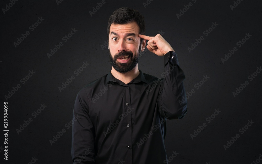 Handsome man with beard making crazy gesture on black background
