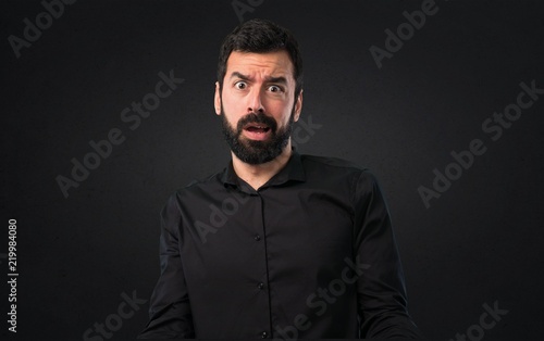 Handsome man with beard stressed overwhelmed on black background © luismolinero