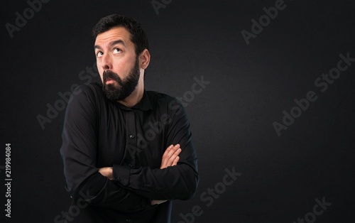 Handsome man with beard making unimportant gesture on black background