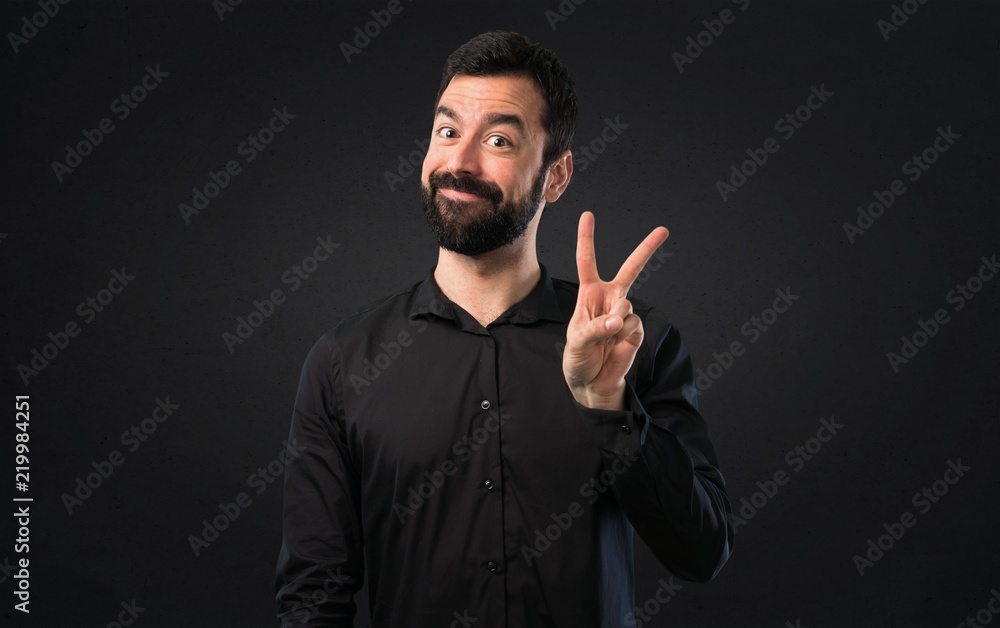 Handsome man with beard making victory gesture on black background Handsome man with beard making victory gesture on black background