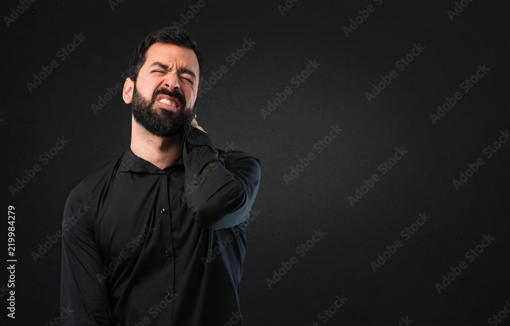 Handsome man with beard with neck pain on black background
