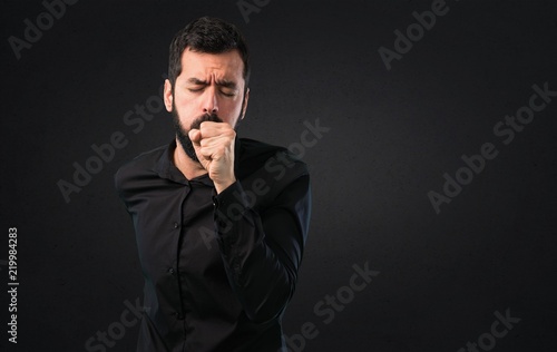 Handsome man with beard coughing a lot on black background