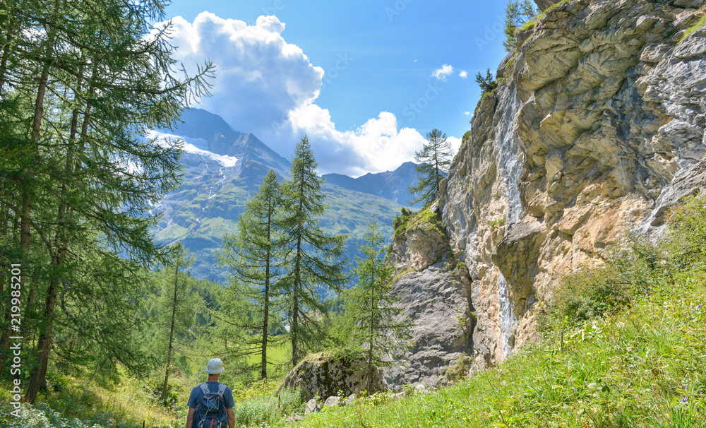 hiking in alpine forest by path crossing cliff in mountain