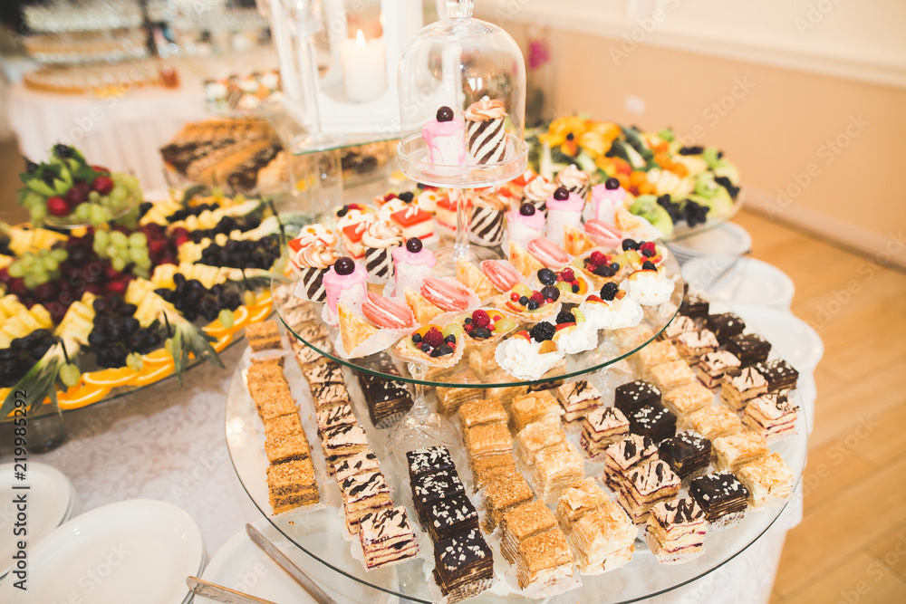 Delicious and tasty dessert table with cupcakes shots at reception closeup Delicious and tasty dessert table with cupcakes shots at reception closeup