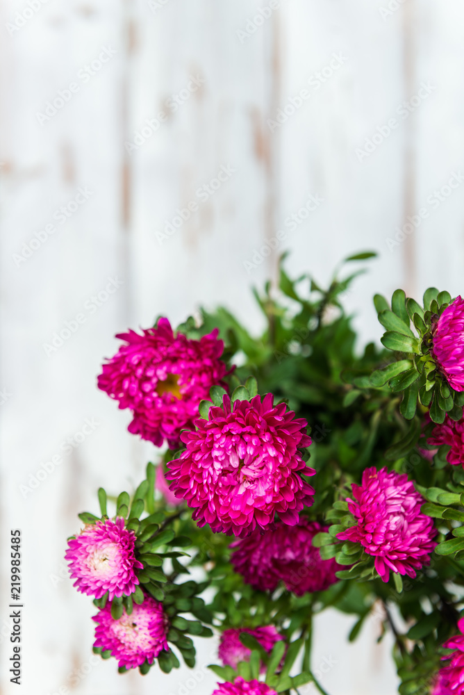 Bouquet of autumn flowers asters on white wooden background