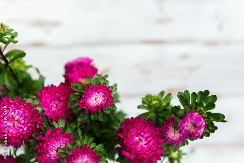 Bouquet of autumn flowers asters on white wooden background