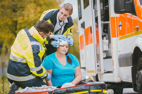 Sanitäter verbinden Kopfwunde von verletzter Frau photo