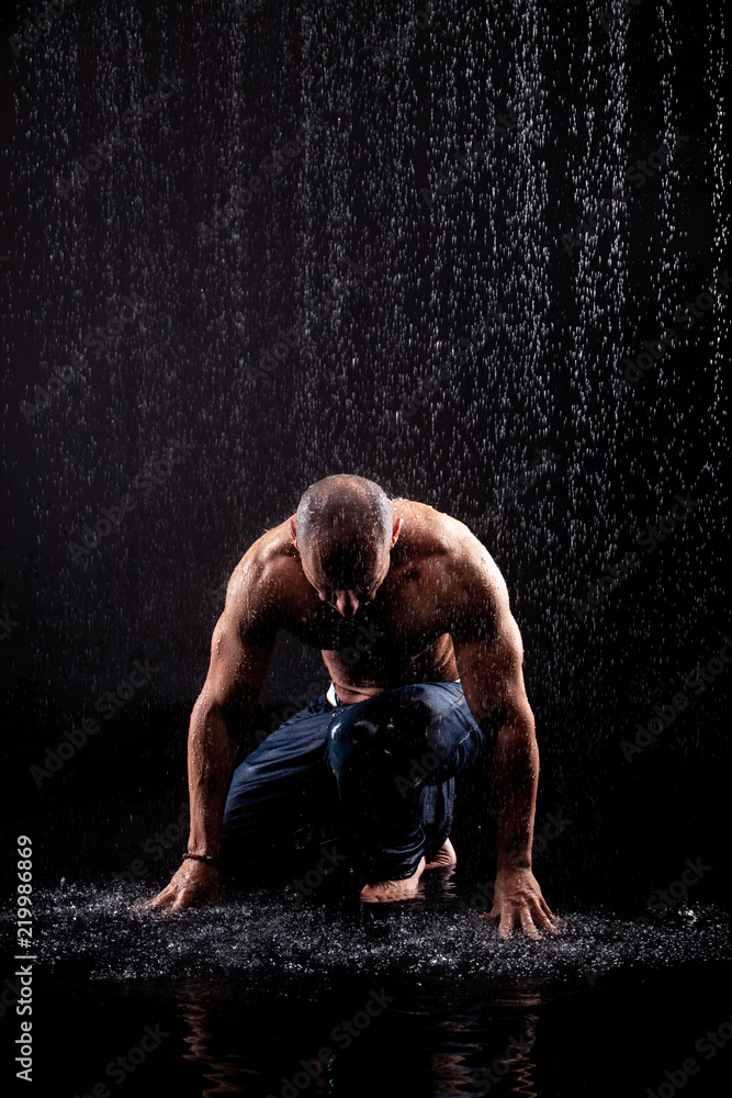 very muscular handsome athletic man striking with a hand on water
