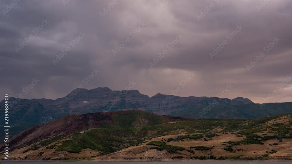 Time lapse of dark clouds moving over mountain range as they light up from the sun setting. Time lapse of dark clouds moving over mountain range as they light up from the sun setting.