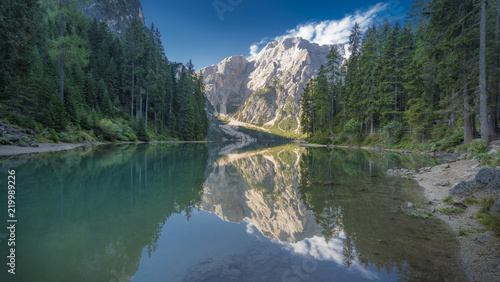 Fototapeta Naklejka Na Ścianę i Meble -  Pragser Wildsee mit sich spiegelnden Bäumen, Bergen und blauem Himmel 