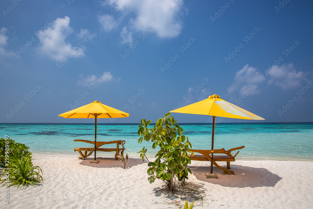 A sun lounger and a beach umbrella on a deserted beach; perfect vacation concept; blue sky; amazing sea