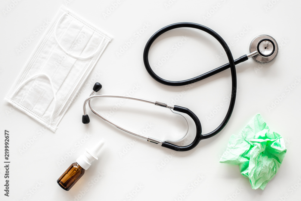 Flu drops. Running nose concept. Wrinkled napkin near stethoscope and face mask on white background top view Flu drops. Running nose concept. Wrinkled napkin near stethoscope and face mask on white background top view
