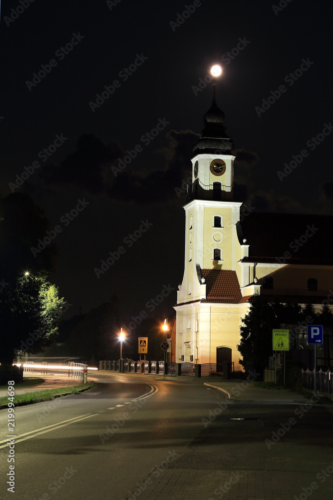 Kościół w nocy, ksjężyc w pełni nad wieżą kościoła.