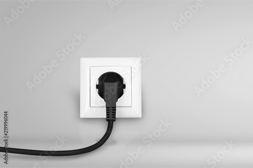 Bilde på lerret White electrical plug in the electric socket on a wall