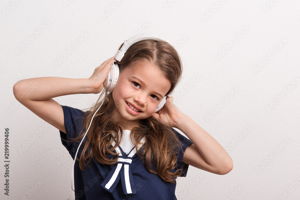 Portrait of a small girl with headphones in a studio. Portrait of a small girl with headphones in a studio.