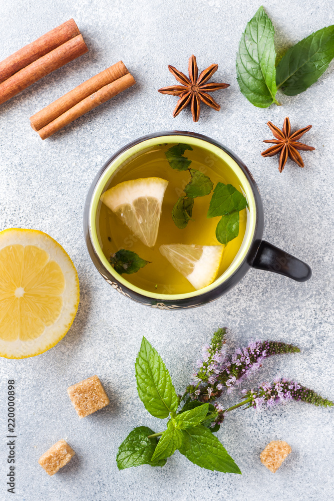 Cup of tea, mint and lemon, brown sugar cinnamon and anise on a grey table Cup of tea, mint and lemon, brown sugar cinnamon and anise on a grey table