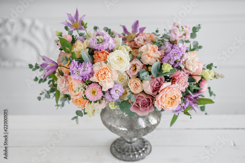 Gorgeous bouquet of different flowers. floral arrangement in vintage metal vase. table setting. lilac and peach color