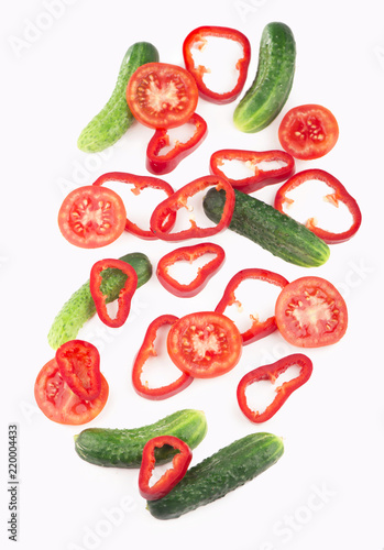 slices of a cucumber tomato and pepper on a white background