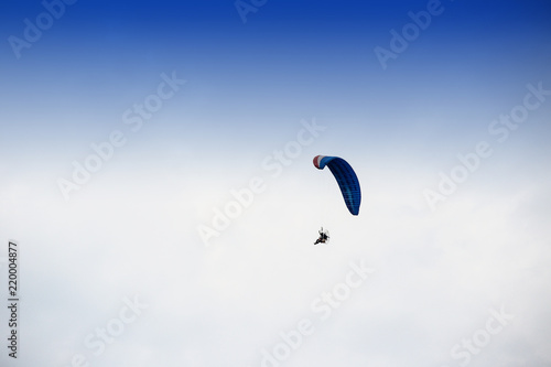 Guy flying on the coloful sky by paramotor kite,extreme activity port. feel freedom like birds. concept overcome the limits of human physiology.