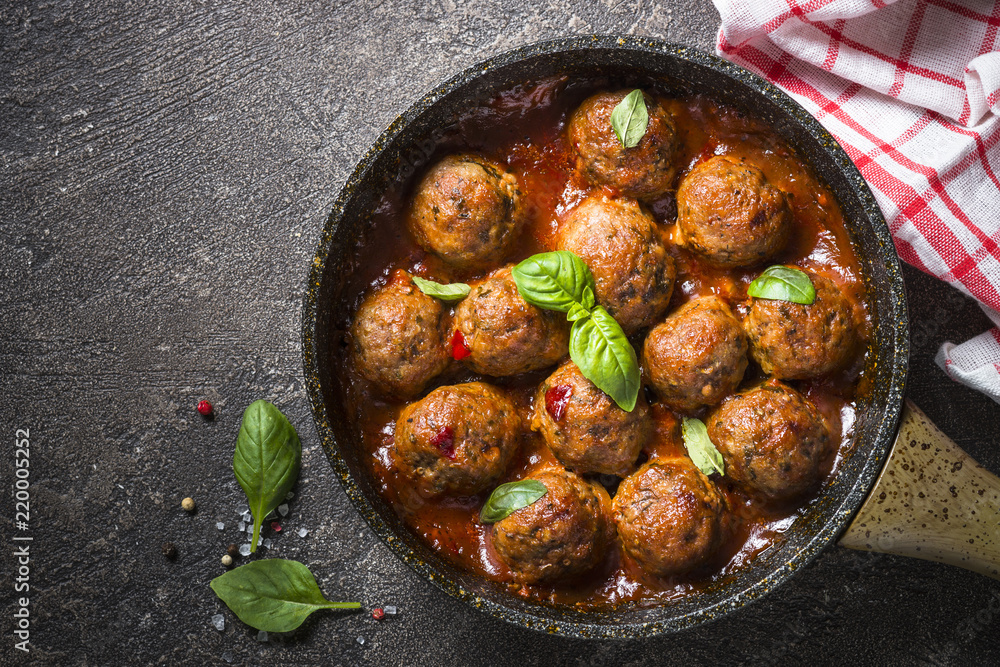 Meatballs in tomato sauce in a frying pan on dark stone table. Meatballs in tomato sauce in a frying pan on dark stone table.
