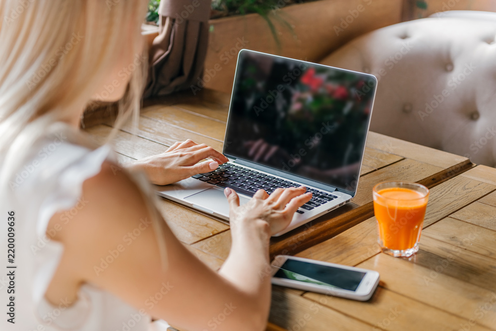 Fototapeta premium Young blonde business woman working on laptop at cafe