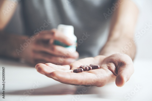 Hands of man holding pill bottle with pills on hand
