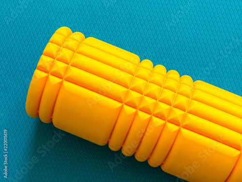 Yellow foam roller on cyan background
