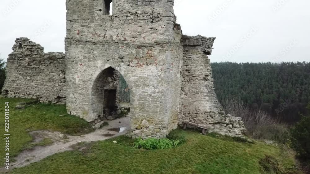 Aerial survey of the ruins of an ancient medieval castle on the top of a wooded mountain and a settlement in the lower reaches Aerial survey of the ruins of an ancient medieval castle on the top of a wooded mountain and a settlement in the lower reaches