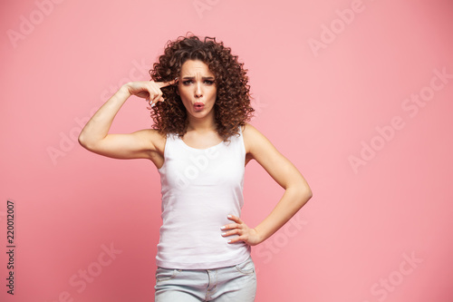 Image of happy young lady standing isolated over pink background. Looking camera pointing.