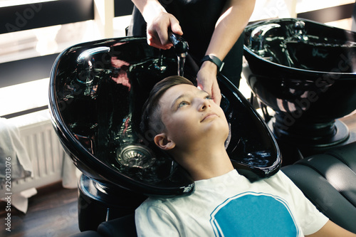 Boy get his hair washed in barder shop photo