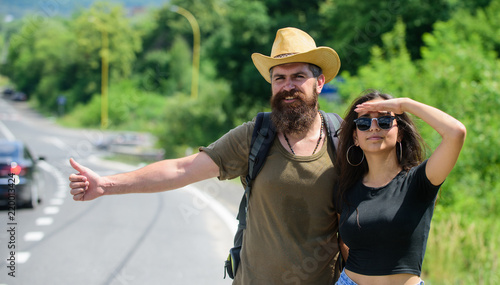 Travellers try to stop car. Couple hitchhikers travelling summer sunny day. Couple travelers man and girl hitchhiking at edge road nature background. Hitchhiking is one of cheapest ways of traveling