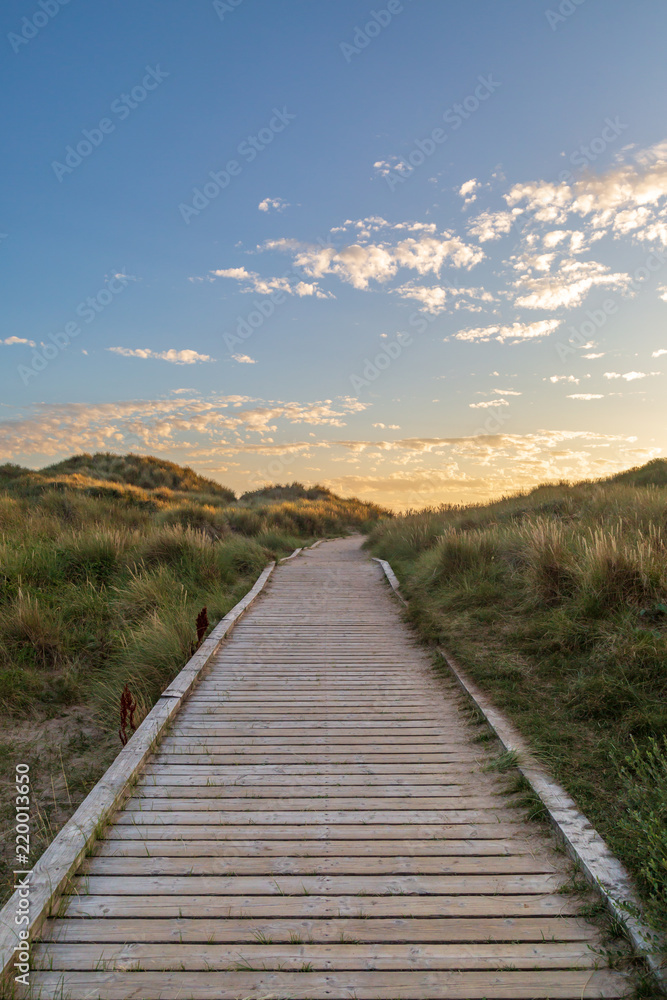 A wooden pathway leading towards the sea at Formby in Merseyside, taken at sunset